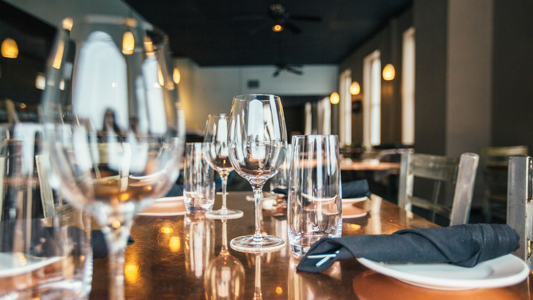 Polished glassware and place settings on a copper-top event table